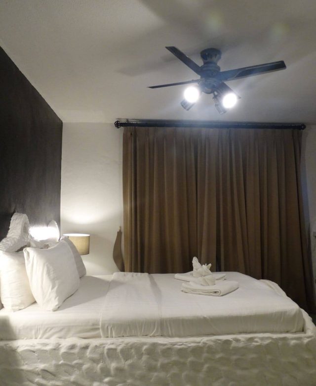 Double Room with balcony and queen bed, featuring TV, ceiling fan, and blackout curtains — 1 min to beach, 5 min to Bangla Road at Big Boys' Bed & Burger - Patong Beach.