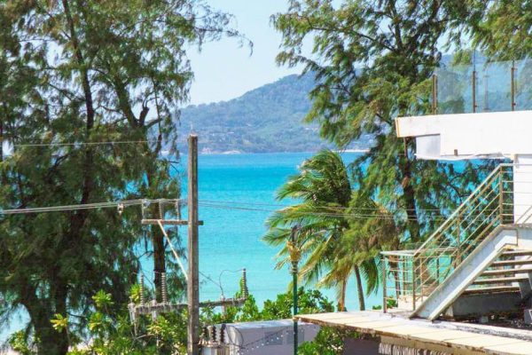 Partial sea view from Family Room balcony with tropical trees and blue water of the sea — 1 min to beach, 5 min to Bangla Road.